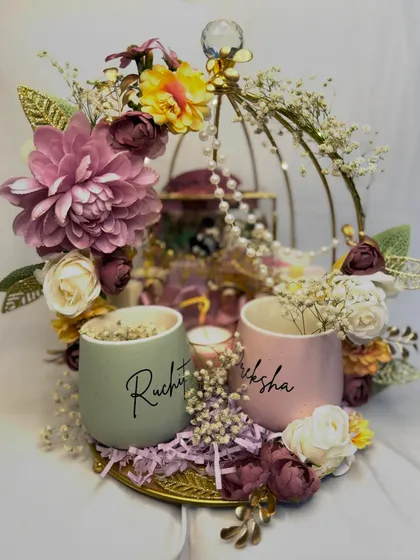 How dreamy is this wedding gift hamper? It features personalized mugs for the couple, a scented candle, and other small gifts, all arranged in a stunning floral birdcage platter.