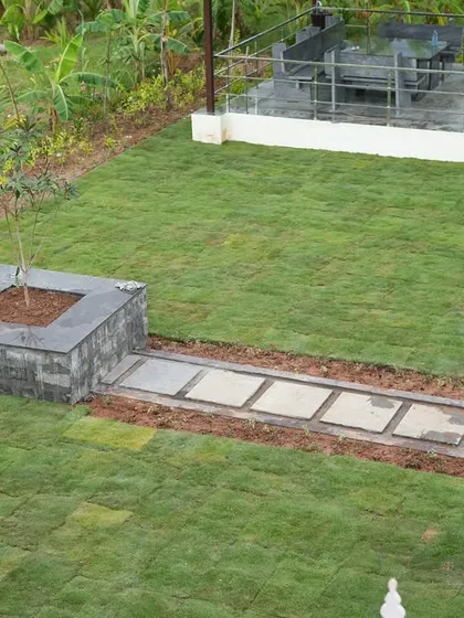 After: An overhead view of the finished lawn, featuring a central tree planter made of dark stone and a clean, functional pathway.