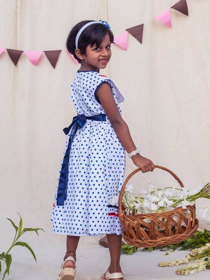A charming back view of the sailor-style polka dot dress, showing the navy sash that ties into a lovely bow. It's a sweet detail that adds to its classic appeal.