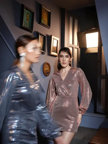 An artistic shot using motion blur to capture the energy of a night out. The focus remains on the model in the rose gold dress, creating a dynamic and visually interesting image.
