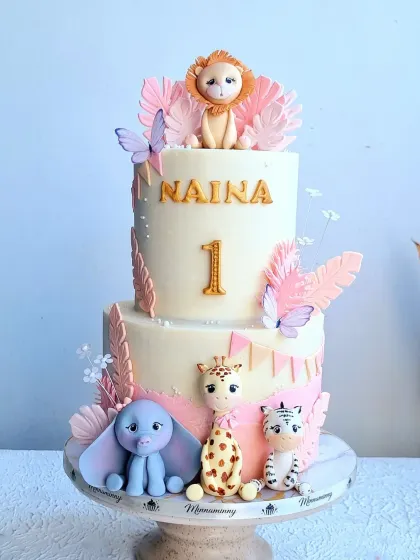 A full view of the pink safari cake, showing its two tiers and the arrangement of the toppers.