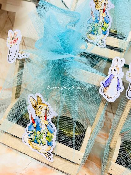 Another look at the Peter Rabbit themed hampers, perfect for a first birthday or a baby shower. The wooden crates and blue net wrapping create a classic, storybook feel.