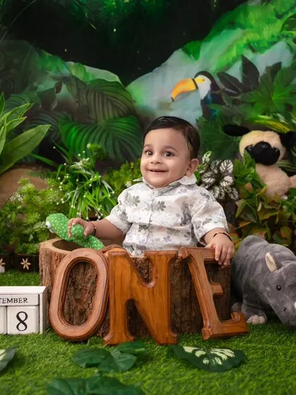 A smiling jungle explorer. The wooden 'ONE' sign marks his first birthday in this adventurous and fun-filled theme.