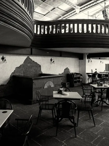 A view of the seating area, showing the contrast between the rough, exposed brick walls and the finished wooden furniture and balcony.