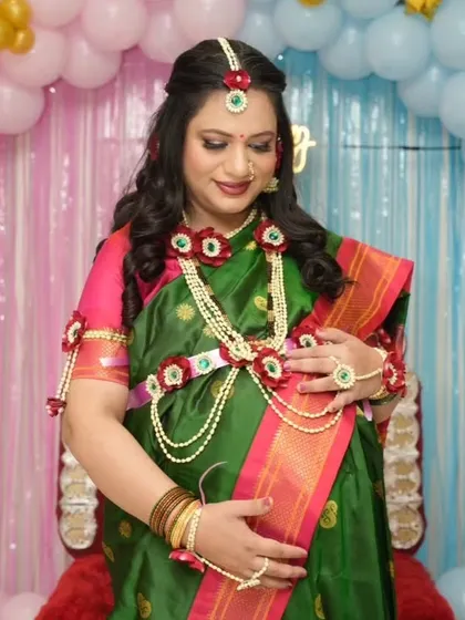 A lovely baby shower look featuring a traditional green saree and beautiful floral jewelry. The makeup is kept soft and pretty to match the occasion.
