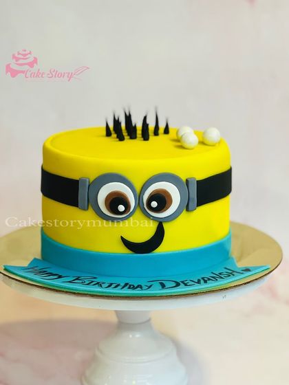 A bright and cheerful Minion cake. This semi-fondant cake is designed to look just like a Minion, complete with his signature goggles and a happy smile.