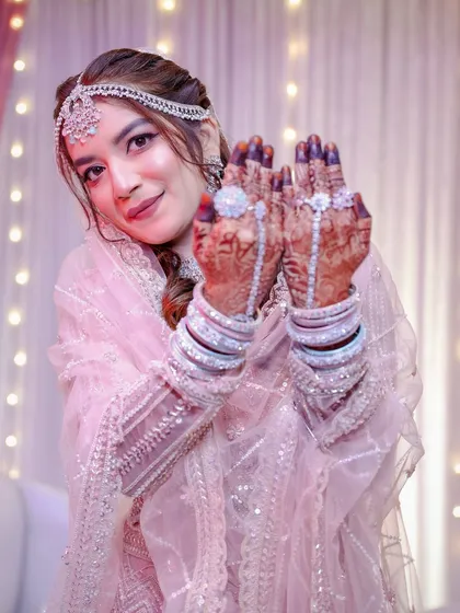 This bride looks like she's stepped out of a fairytale in her shimmering pink lehenga. The makeup is soft and romantic, with a focus on glowing skin and eyes that sparkle.