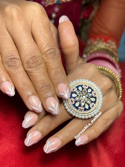 Simple, clean, and elegant. This design uses a nude base with delicate white swirls and a hint of glitter, making it a perfect choice for a sophisticated wedding look.