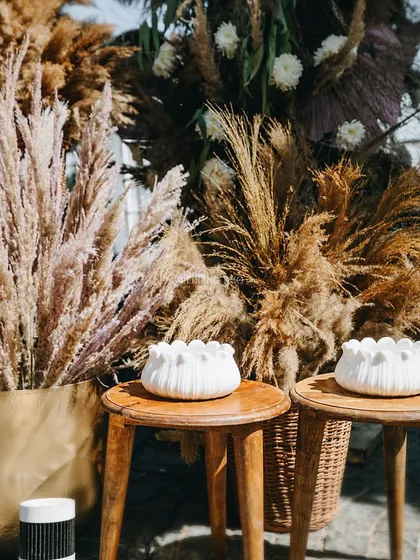 Details of our nature-inspired decor. Dried pampas grass and botanicals are paired with white, lotus-shaped candle holders, creating a serene and earthy tablescape.