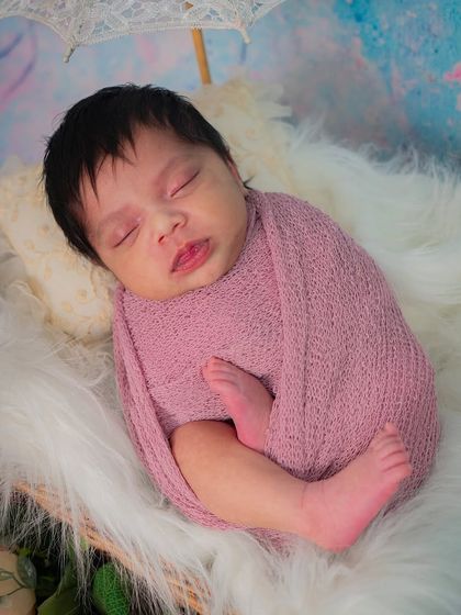 A close-up of a newborn wrapped in a pink swaddle, showing her tiny feet. This pose is a classic for highlighting how small and precious they are.