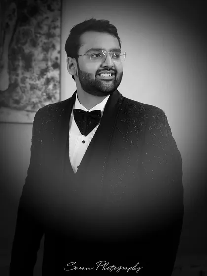 A classic black and white portrait of the groom looking dapper in his tuxedo.