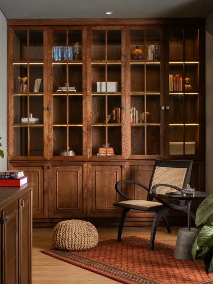 A custom-built library cabinet with integrated lighting provides a beautiful display for books and objects, adding to the study's warm, traditional feel.