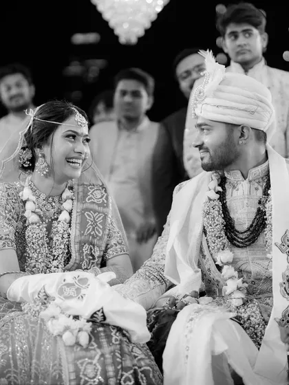 The shared smiles between Krunal and Rashmi during their wedding ceremony. This monochrome shot focuses purely on their connection and the happiness they find in each other's presence.