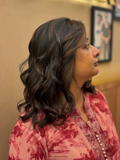 A side view of a client's hair with subtle, natural-looking highlights. The soft waves and gentle color create a timeless and elegant style.