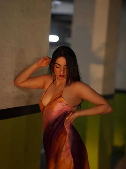 A confident pose in a multi-colored satin dress against a dark background, making the colors pop.