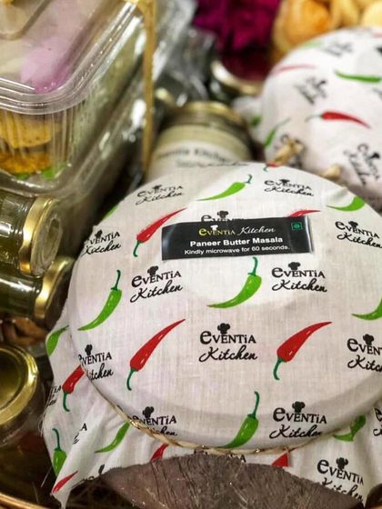 My signature Paneer Butter Masala, packed in a bowl with a custom-branded cloth cover. I take care to package every dish securely and beautifully, so it arrives at your home ready to be enjoyed.