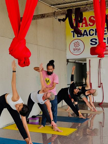In Trikonasana, or Triangle Pose, proper alignment is crucial. I am adjusting a student to ensure her spine is long and her chest is open, demonstrating the finer points of the asana.