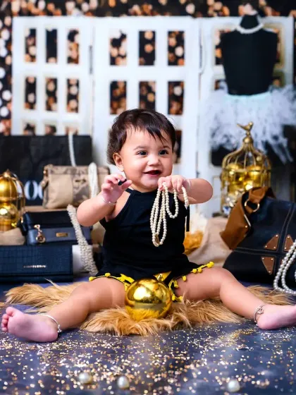 This baby boy is having a great time playing with a string of pearls in this fashionable and fun photoshoot.