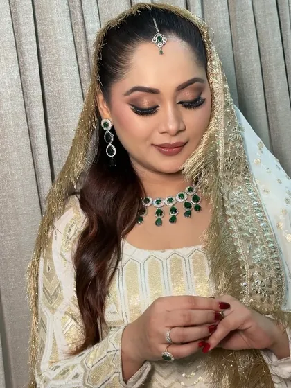 A serene portrait of the bride with her dupatta. The soft brown and gold eyeshadow adds warmth to the look, while her skin remains dewy and fresh.