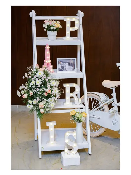A decorative detail from the Parisian party. We used a white ladder shelf to display light-up letters spelling "PARIS," a mini Eiffel Tower, and fresh flowers, creating a charming photo-worthy vignette.