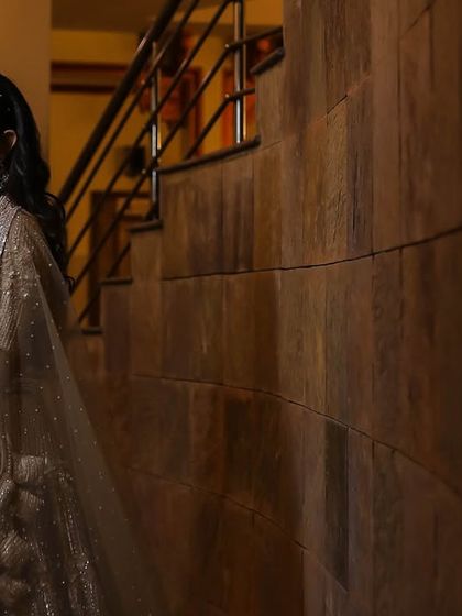 A portrait of a bride leaning against a textured wall, the soft lighting highlighting her features and her elegant gown.