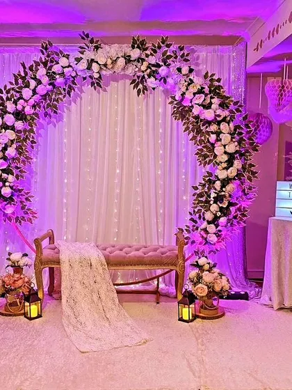 A dreamy and romantic setup for an evening function. This decor uses a floral moon-gate arch with purple uplighting and fairy lights to create a magical atmosphere.