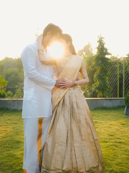 An artistic shot of a couple in traditional outfits, with the setting sun creating a beautiful flare between them. This silhouette-style portrait is both romantic and creative.