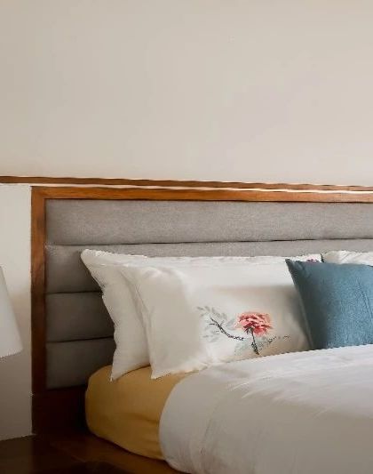 A close-up of the upholstered headboard on my live-edge bed, showing the texture of the fabric and the warm teak frame.