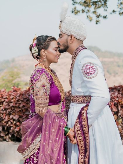 A beautiful forehead kiss, a classic wedding portrait. The bride's makeup is soft and romantic, perfect for these intimate shots.