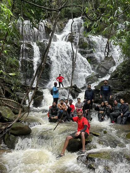 A group posing for a photo in front of a cascading waterfall, a perfect memory from a day spent exploring the wild.