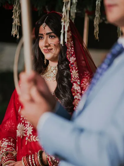 A close-up of the bride, Anisha, during her phoolon ki chadar entry. Her serene expression and beautiful red attire are the focus of this emotional shot.