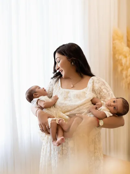 A mother's love. She holds her two newborn babies, sharing a beautiful, interactive moment. These are the precious memories I love to capture for families.