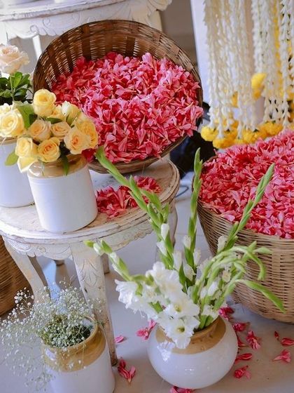 Baskets filled with fresh marigold and rose petals, ready for the Haldi ceremony, alongside vases of fresh flowers.
