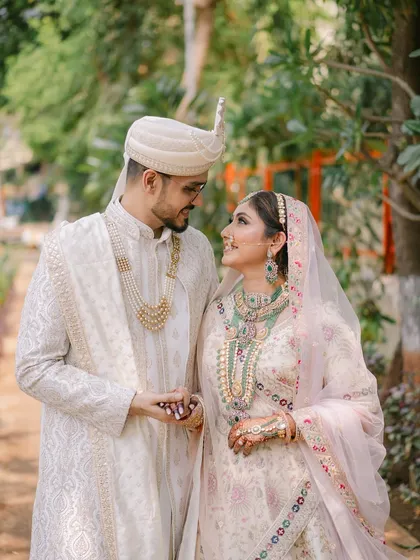 A quiet, romantic moment between the couple. The bride's pastel lehenga and emerald jewelry are complemented by a soft glam makeup look that enhances her natural beauty.
