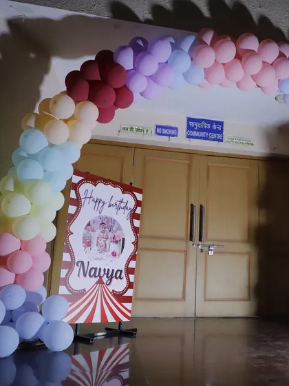The entrance to the community center decorated with a pastel rainbow balloon arch for a first birthday party.
