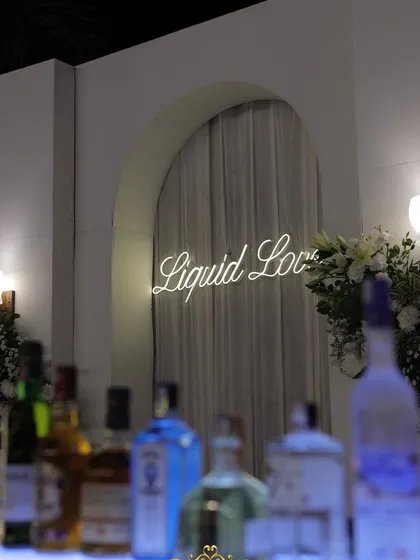 A close-up of the "Liquid Love" neon sign, adding a playful and modern touch to the sophisticated bar area.
