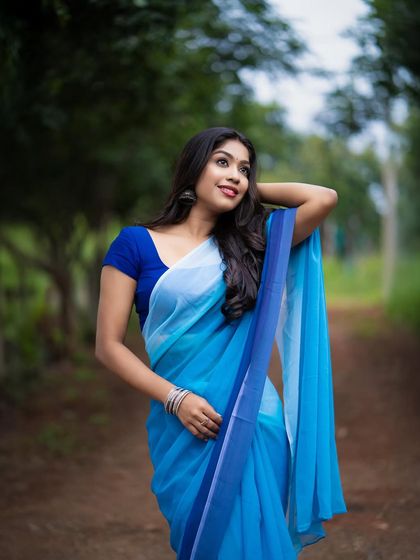 An outdoor portrait featuring a beautiful blue ombre saree. The natural lighting and the movement in the fabric create a soft, ethereal look, perfect for a fashion lookbook.