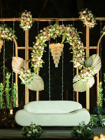 Showcasing a chic and modern reception stage with a boho-rustic vibe. The blend of floral arches, pampas grass, and elegant chandeliers creates a sophisticated yet earthy ambiance.