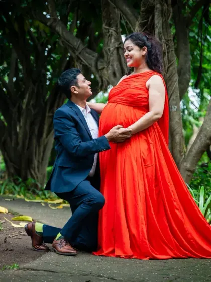A truly romantic gesture. Here, the dad-to-be is on one knee, lovingly holding the baby bump, surrounded by the beautiful, natural setting of a garden.
