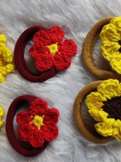 A pair of red floral scrunchies and a pair of sunflower scrunchies. These are great for adding a fun, floral touch to a simple ponytail.