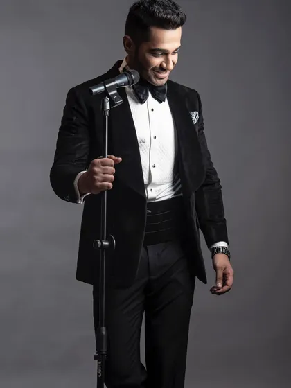 The same velvet tuxedo, captured in a moment of performance. The richness of the velvet and the sharp lines of the tailoring create an unforgettable stage presence.