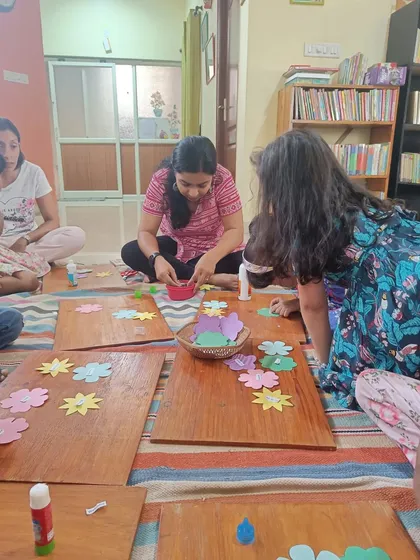 The storyteller helps distribute materials for the craft, ensuring everyone has what they need to get started.
