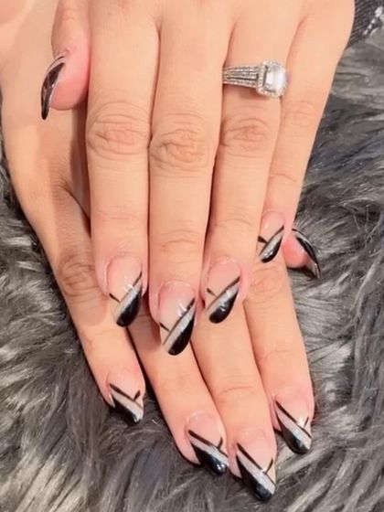 A graphic black and silver design on almond nails, using diagonal lines to create a sharp, modern pattern.