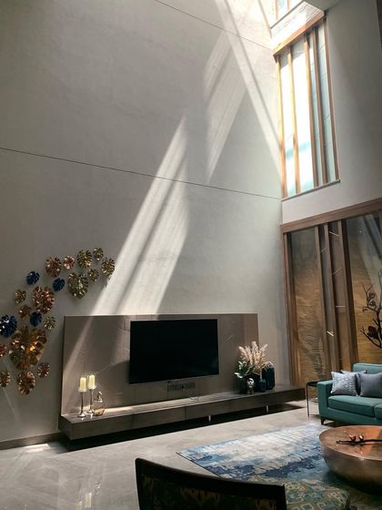 A double-height living space where a dramatic shaft of sunlight streams in from a high skylight. The light moves across the wall throughout the day, becoming a living element within the serene, art-filled room.