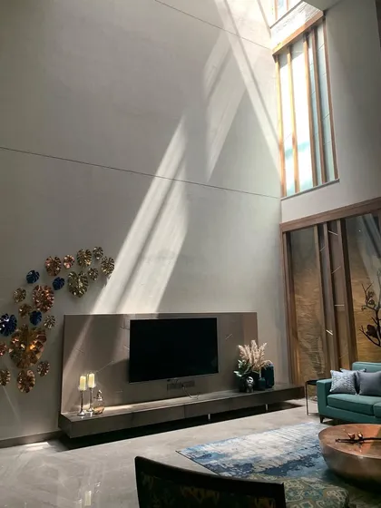 A sunbeam cuts across a double-height living space, highlighting the volume and the art on the wall. The strategic placement of windows and skylights is key to creating homes that are filled with natural light and a sense of well-being.