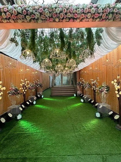 A lovely peach-themed entrance passage. The design uses a floral arch, a canopy of hanging birdcages, and tree-like light props to create a warm and enchanting walkway.