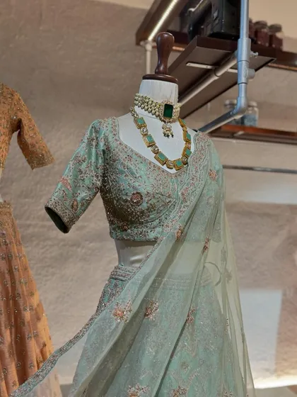 A close-up of this mint green lehenga, highlighting the delicate floral embroidery on the blouse and the elegant emerald and polki necklace that completes the look.