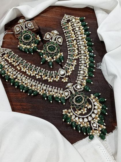 A layered necklace set with a long Rani Haar and a matching choker. This design is perfect for brides, featuring rich green or red stones and intricate detailing for a complete and opulent look.