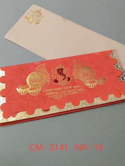 A bright red folded invitation card perfect for a traditional Hindu wedding. It is adorned with gold foil Ganesha, shehnai, and Sanskrit shloka details.