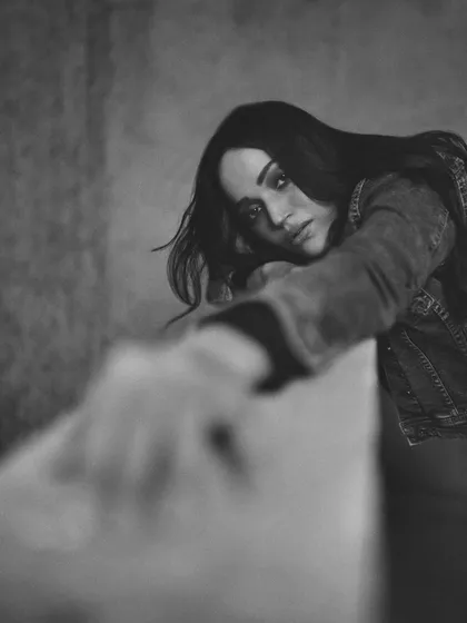An artistic shot that uses foreground blur to draw the viewer's eye to the subject's face, creating a sense of depth and longing.